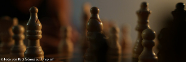 eine Nahaufnahme eines Schachbretts mit einer Person im Hintergrund